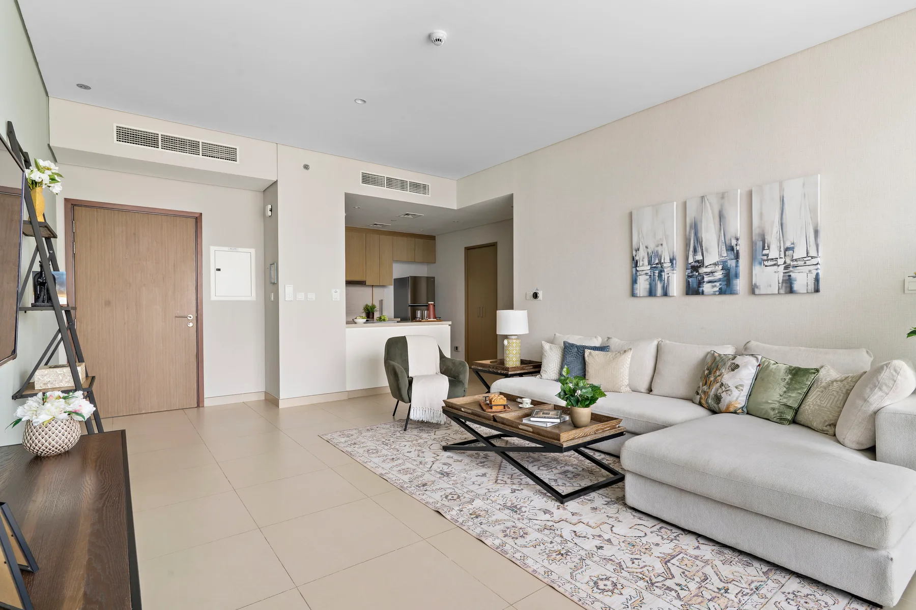 Una sala luminosa con sofá seccional, mesa de centro y cocina abierta.