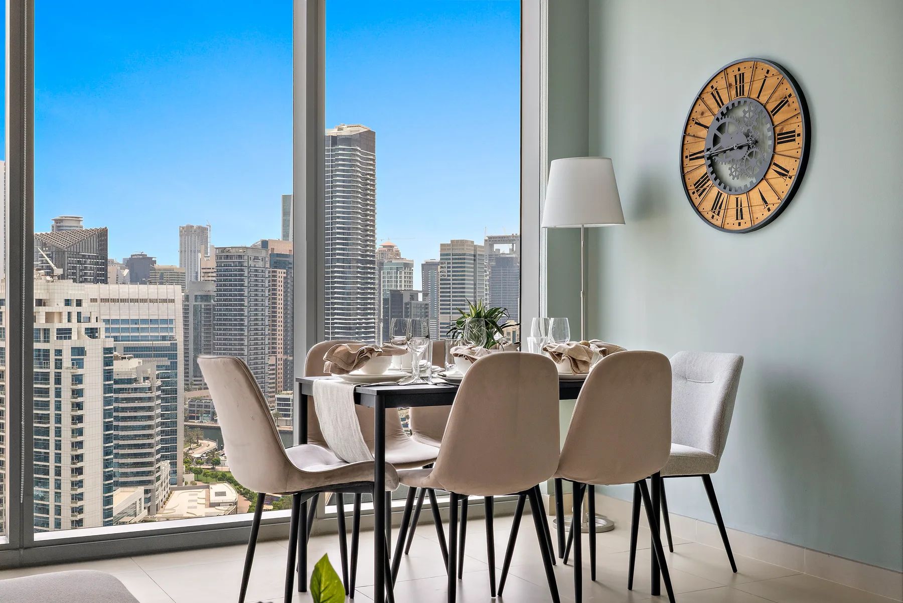 Comedor con la mesa puesta y edificios de la ciudad visibles a través de grandes ventanas.