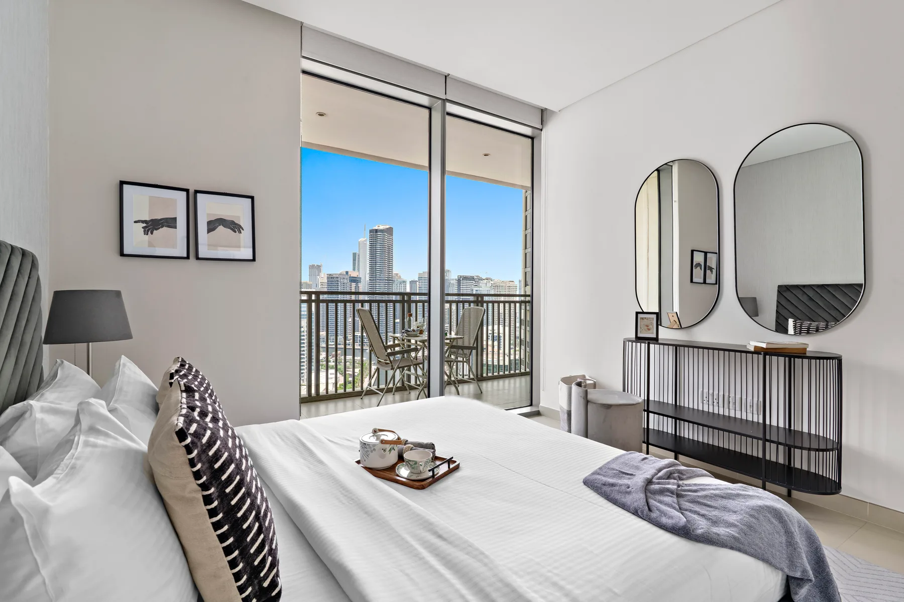 Un dormitorio luminoso con una cama bien arreglada y puertas de vidrio que dan a un balcón.