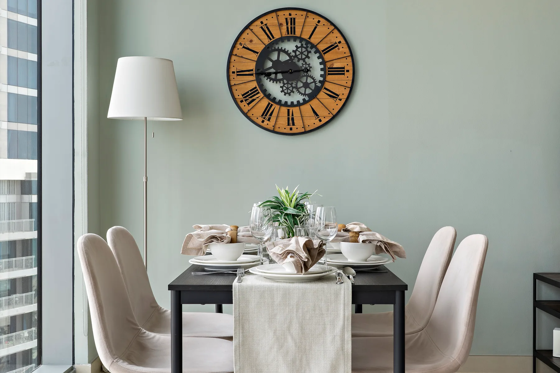 Un comedor con la mesa puesta y un gran reloj de pared.