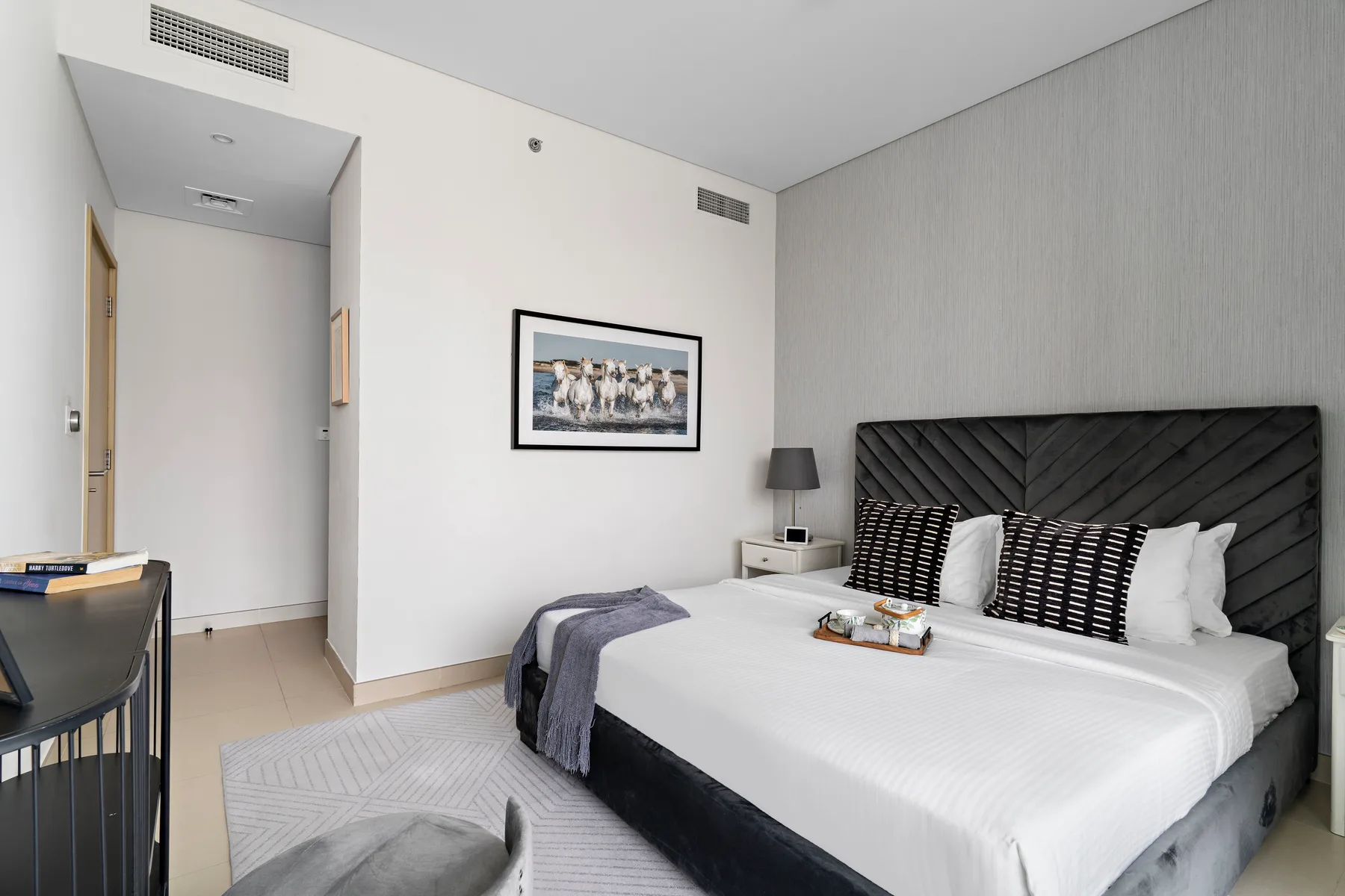 Un dormitorio con una cama grande, cojines estampados y arte enmarcado en la pared.