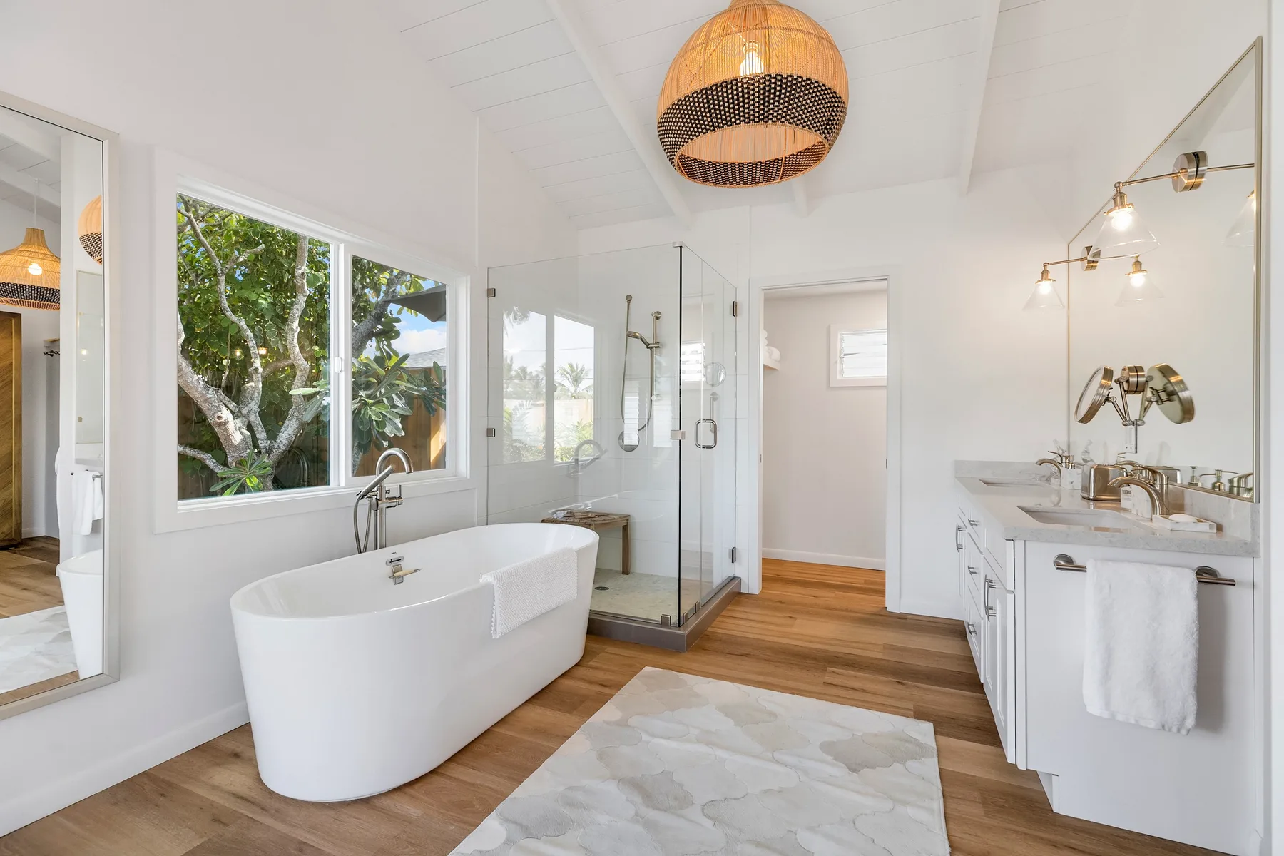 Un baño luminoso con bañera independiente, ducha de vidrio y lavabo doble.