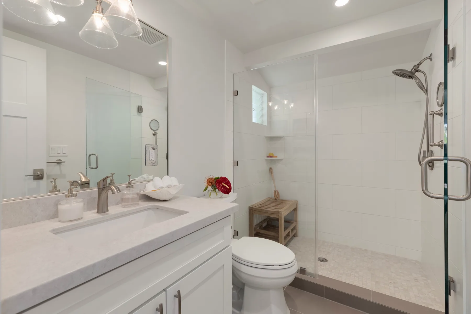 Un baño luminoso con lavabo, inodoro y ducha de cristal.