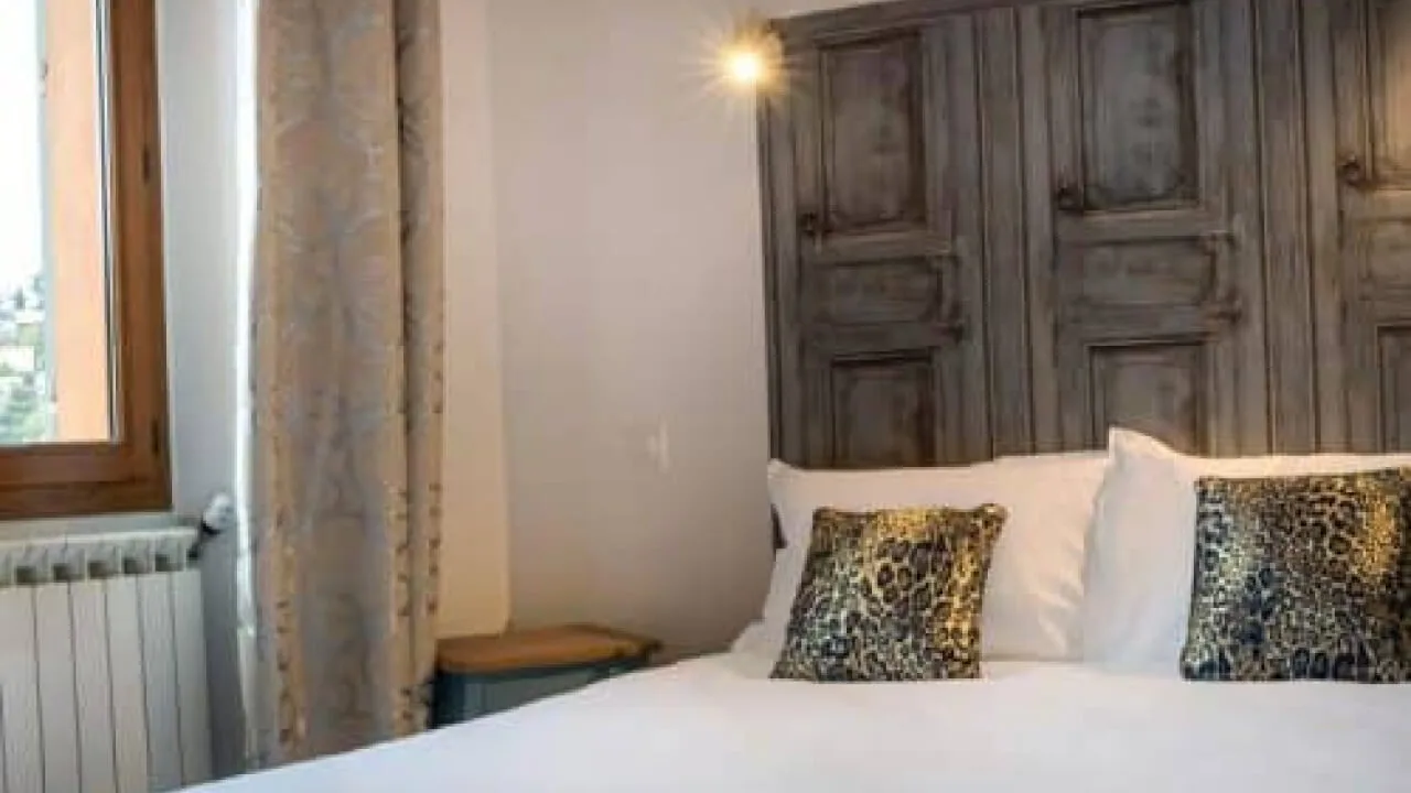 Hotel room with a bed, pillows and wooden headboard.
