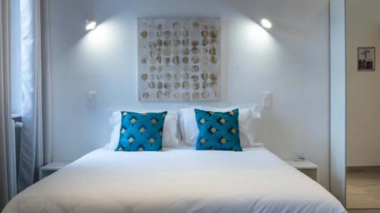 Modern room with blue cushions on a white bed.
