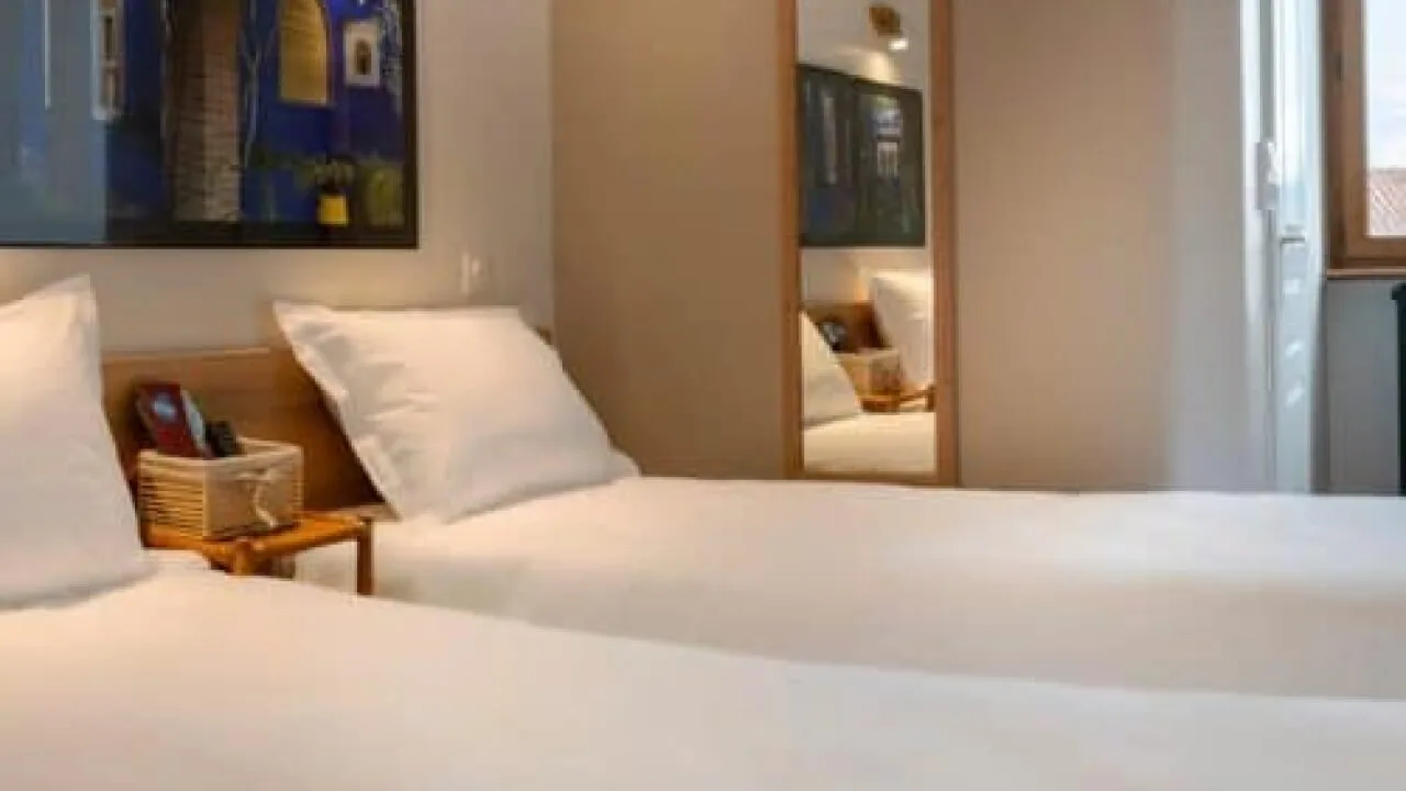 Hotel room with two single beds and a mirror.