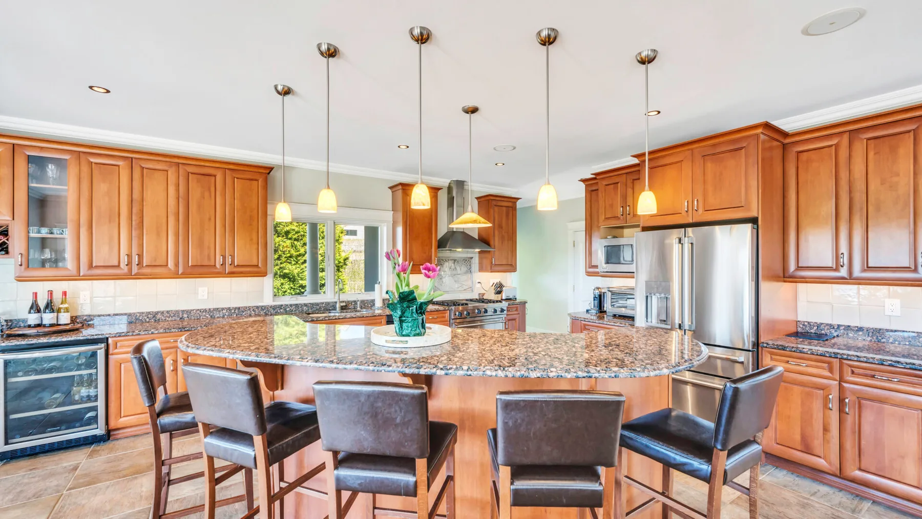 Una cocina amplia cuenta con gabinetes de madera y una gran isla central con asientos.