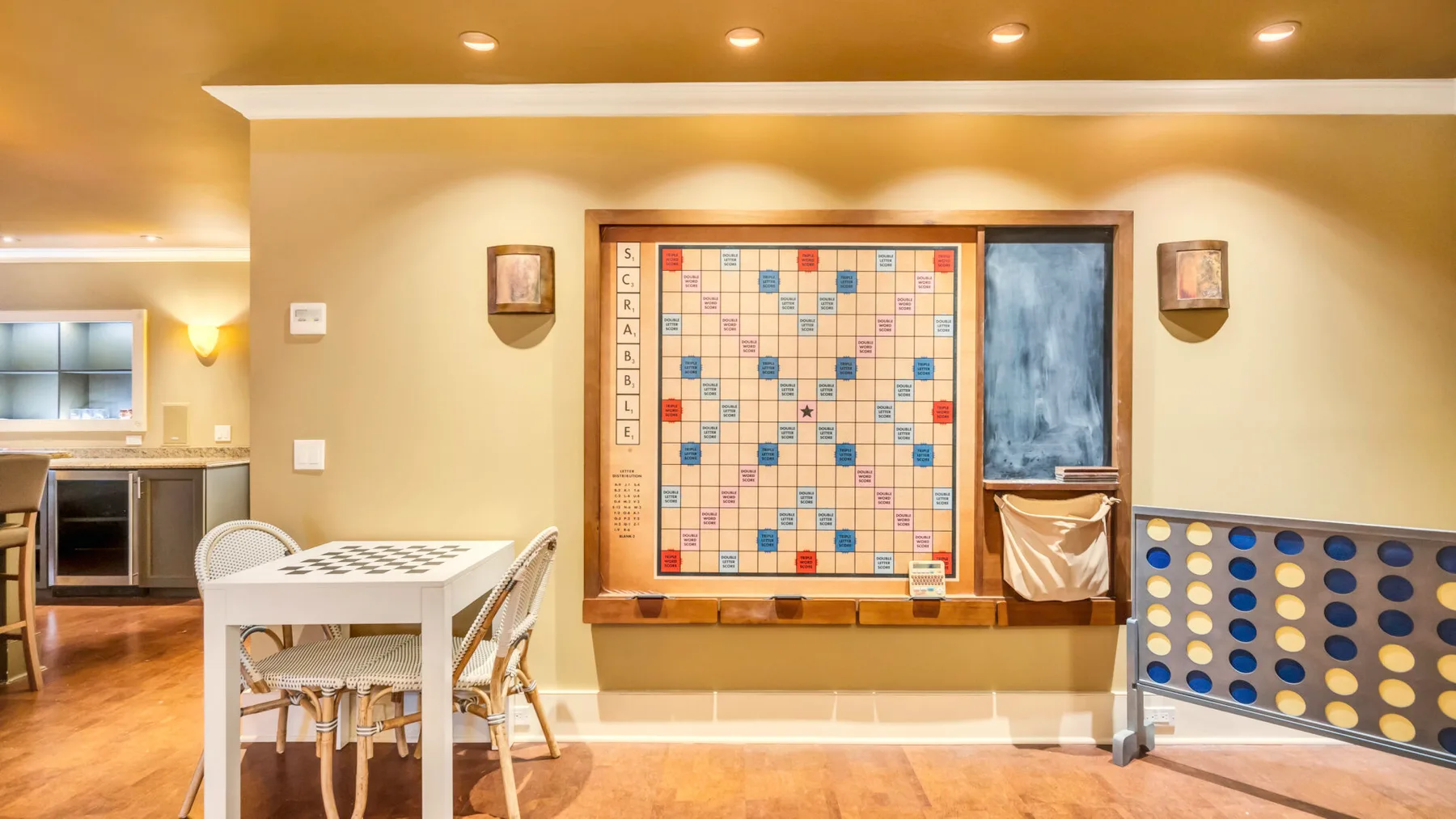 Una zona de juegos con un tablero de Scrabble y un juego de Conecta Cuatro junto a una mesa pequeña.
