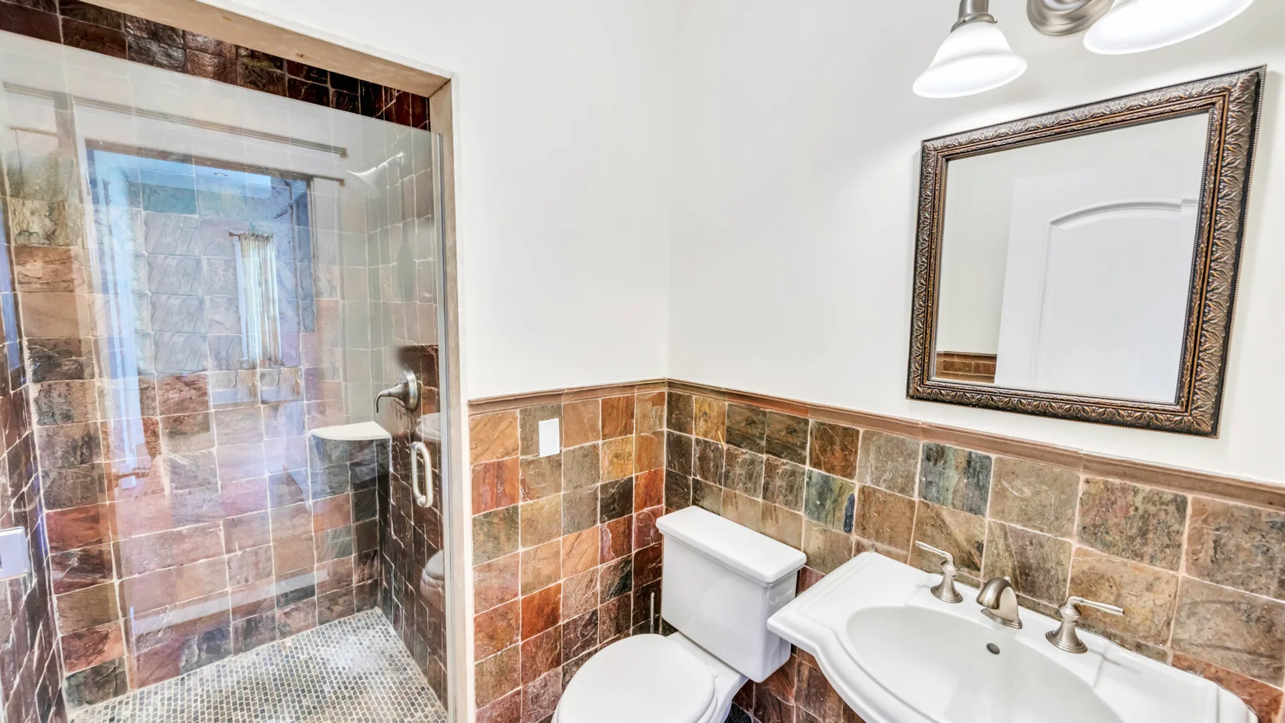 Un baño con ducha de vidrio, inodoro y lavabo.