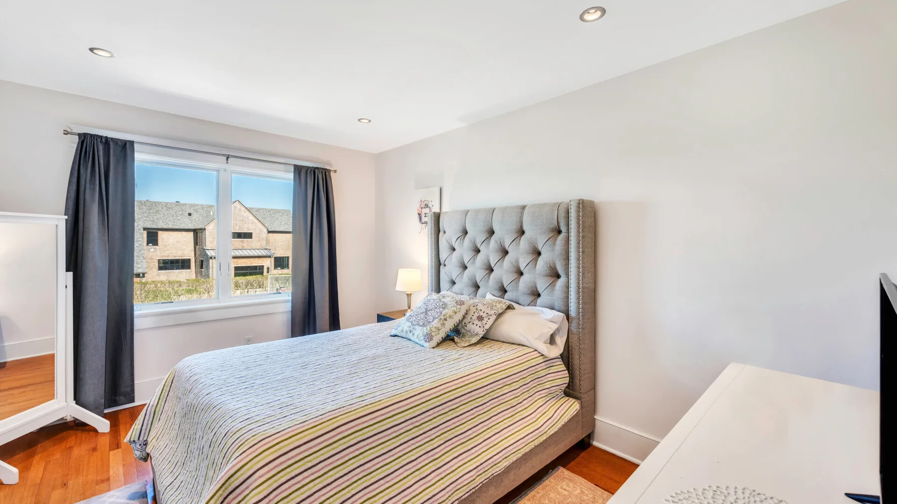 Un dormitorio luminoso con una cama junto a una ventana enmarcada por cortinas oscuras.