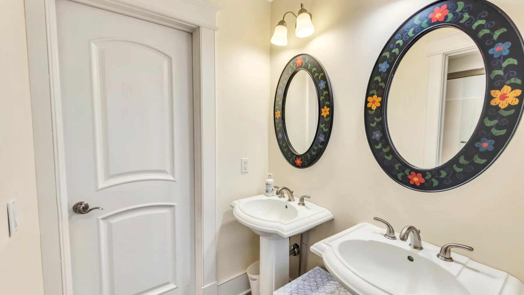 Un baño con dos lavabos y espejos con marcos florales.