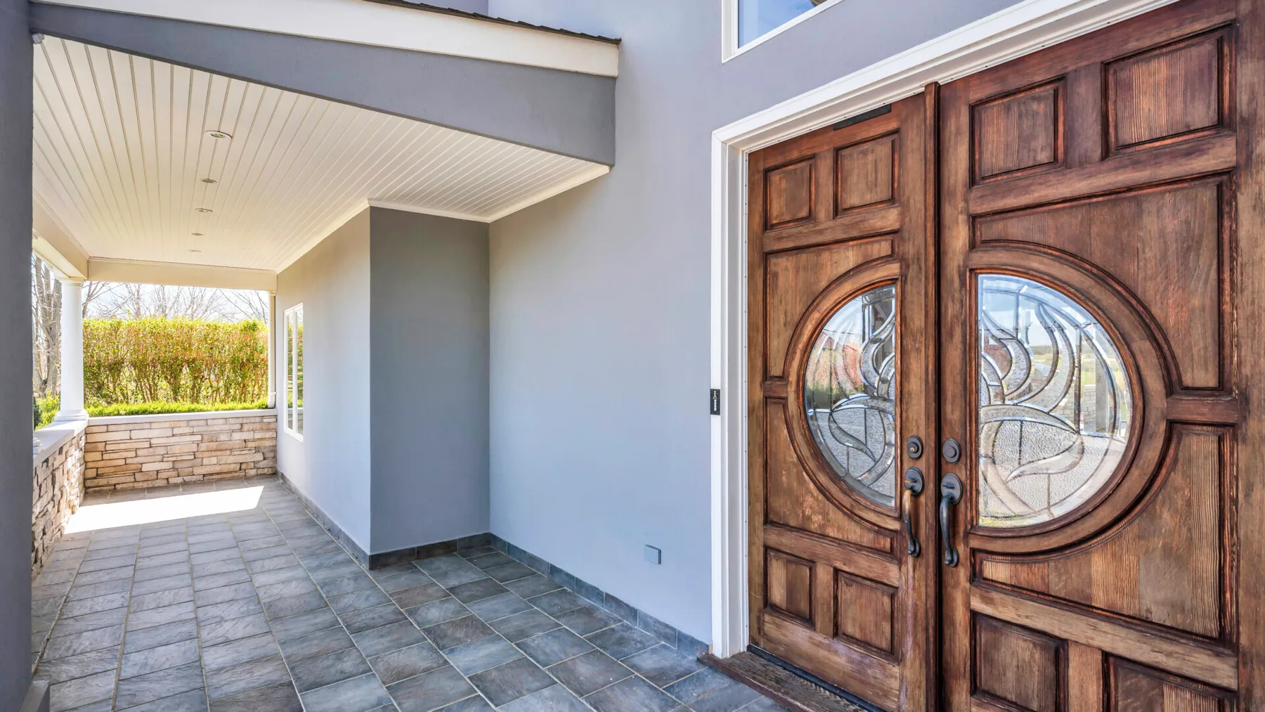 Una entrada cubierta con suelo de baldosas y puertas dobles de madera decoradas.