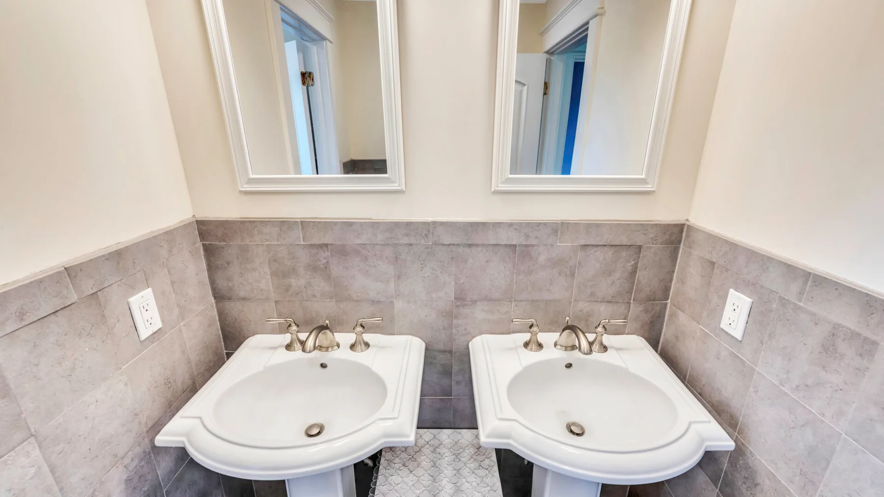 Un tocador de baño con dos lavabos bajo espejos de pared.