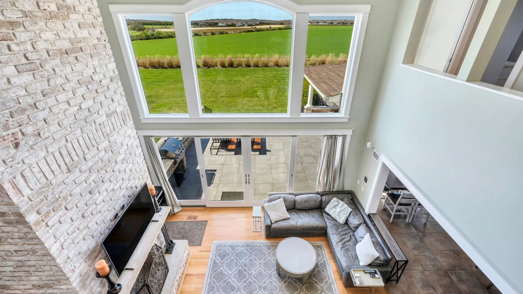 Una sala luminosa con una zona de estar, grandes ventanas y vistas a campos verdes.