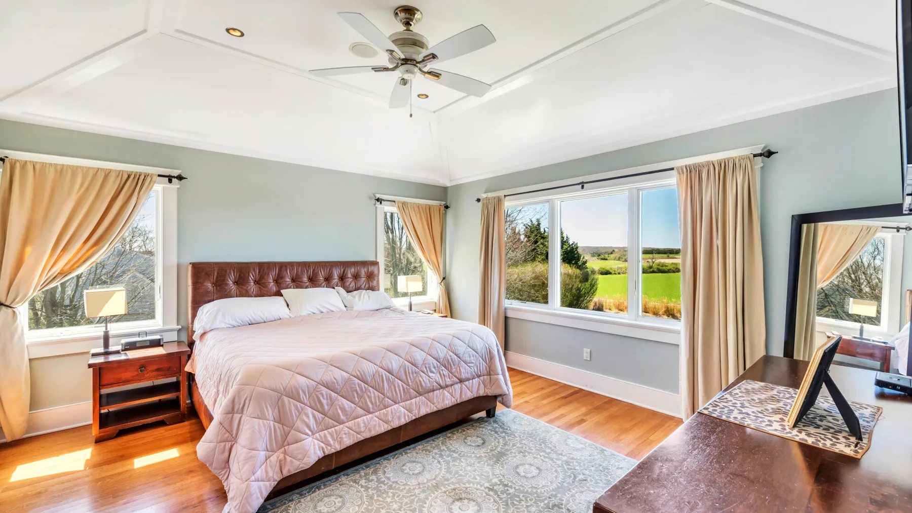 Un dormitorio luminoso con una cama grande junto a ventanas con vistas a zonas verdes.
