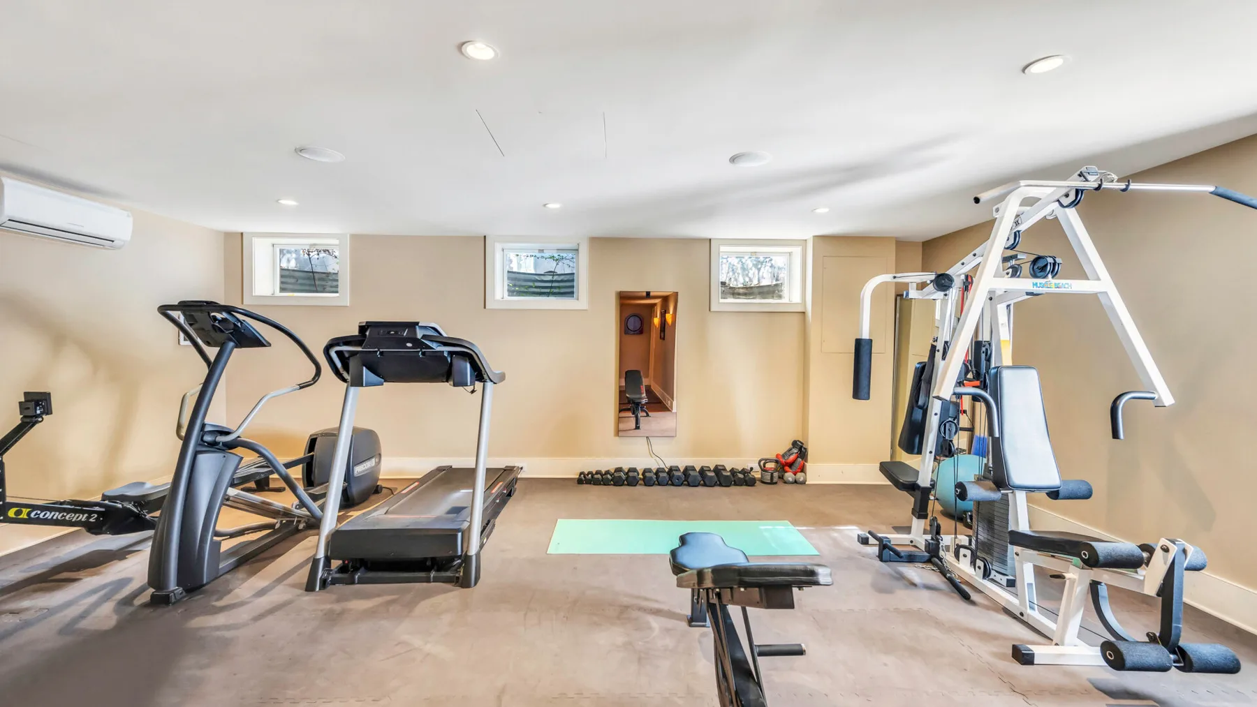 Un gimnasio con cintas de correr, pesas y equipo de entrenamiento de fuerza.