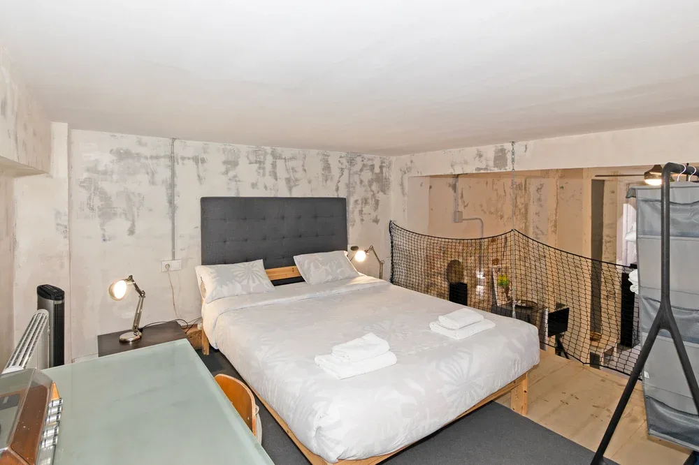 A bedroom with a neatly made bed and a desk beside it.