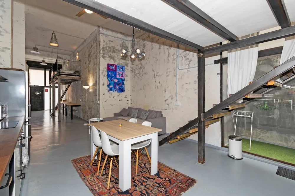 Una zona abierta de estar y comedor tiene una mesa, asientos y una escalera.