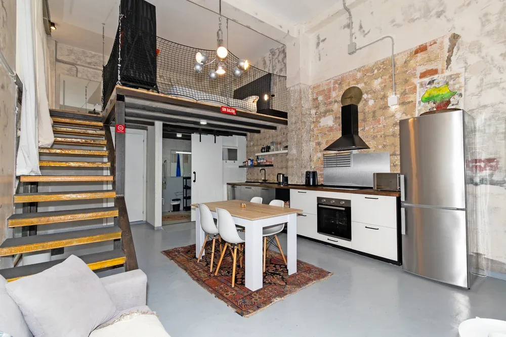 An open-plan kitchen and dining area with a table, seating, and a staircase.