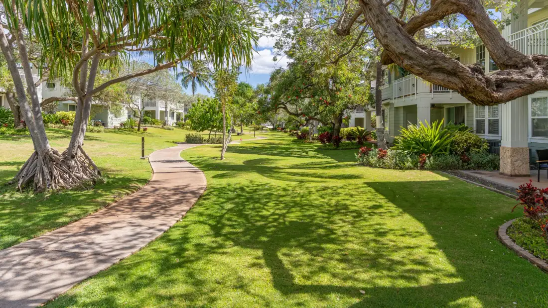 A landscaped garden path winds through green lawns beside residential buildings.