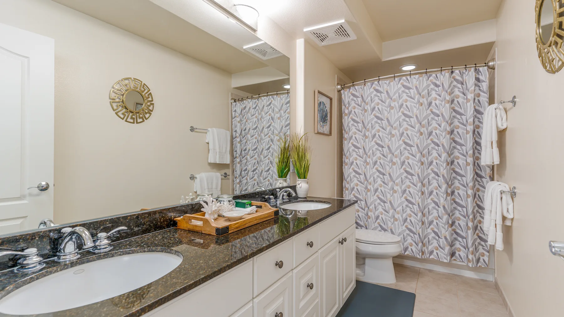 A bathroom vanity with a wide countertop stands beside a curtained bathtub.