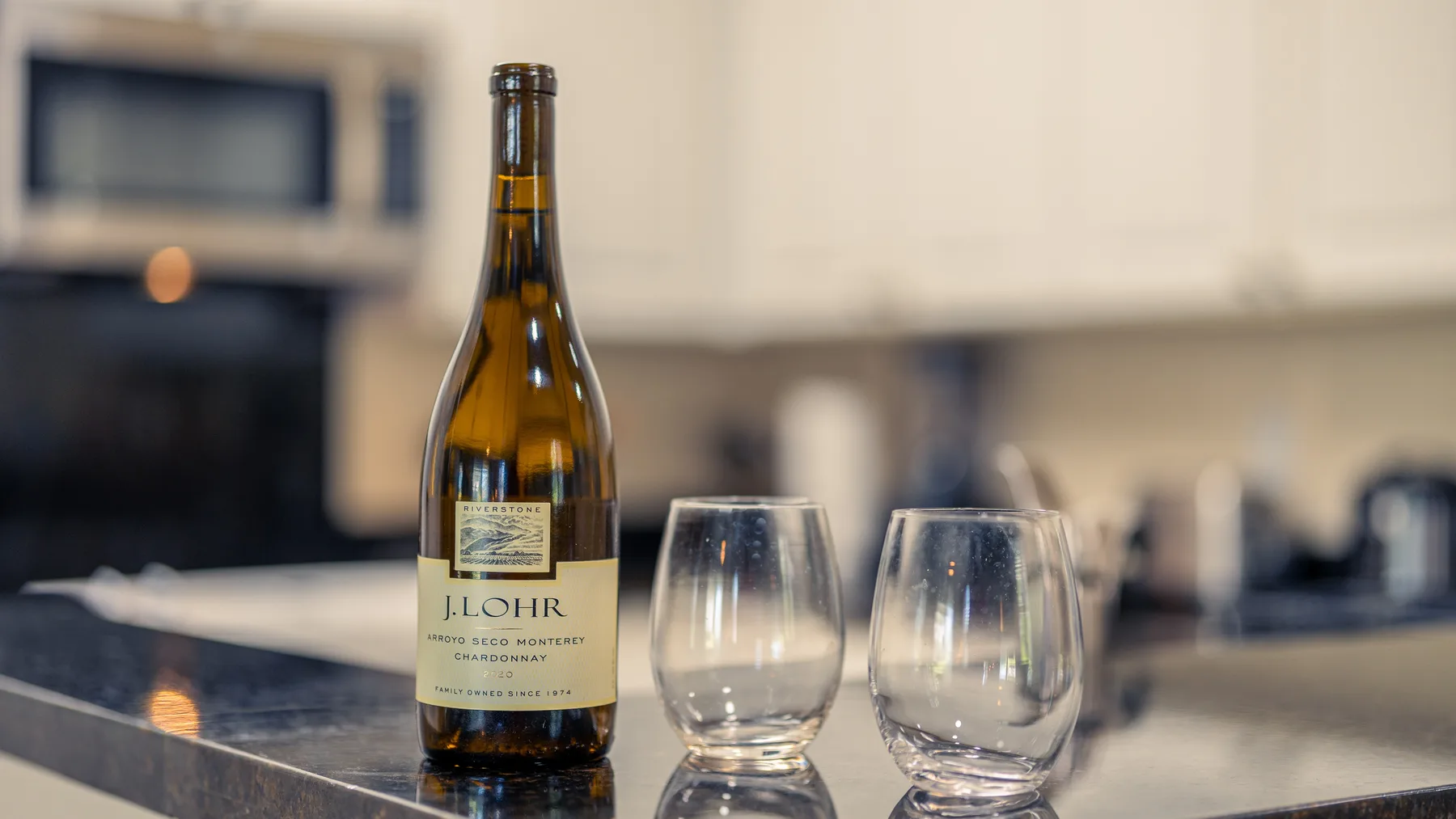 A kitchen counter displays a wine bottle and two glasses.