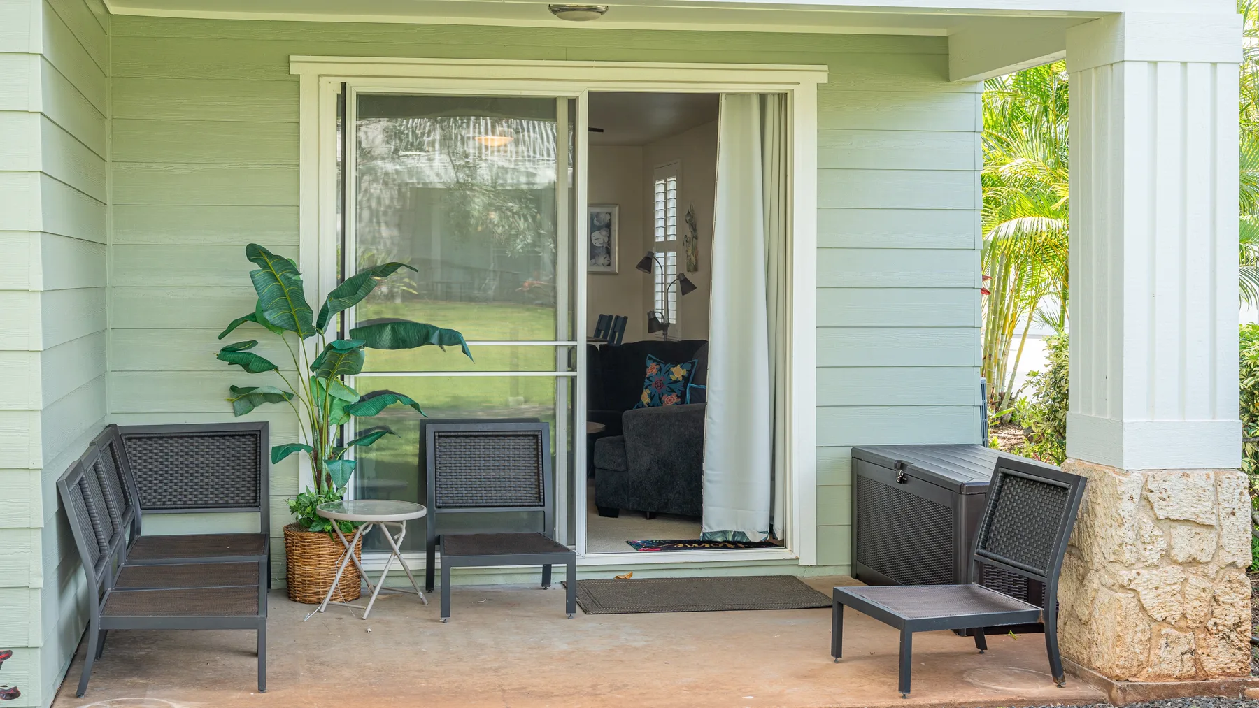 A covered patio with seating and an open sliding glass door.