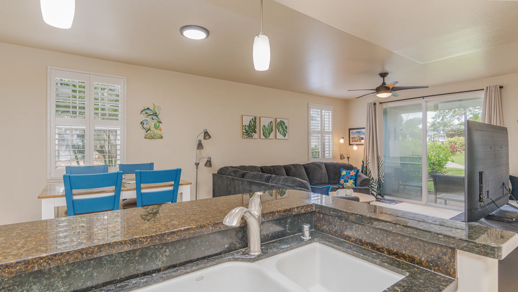An open-plan kitchen and living area with a counter, dining table, and sliding glass doors.