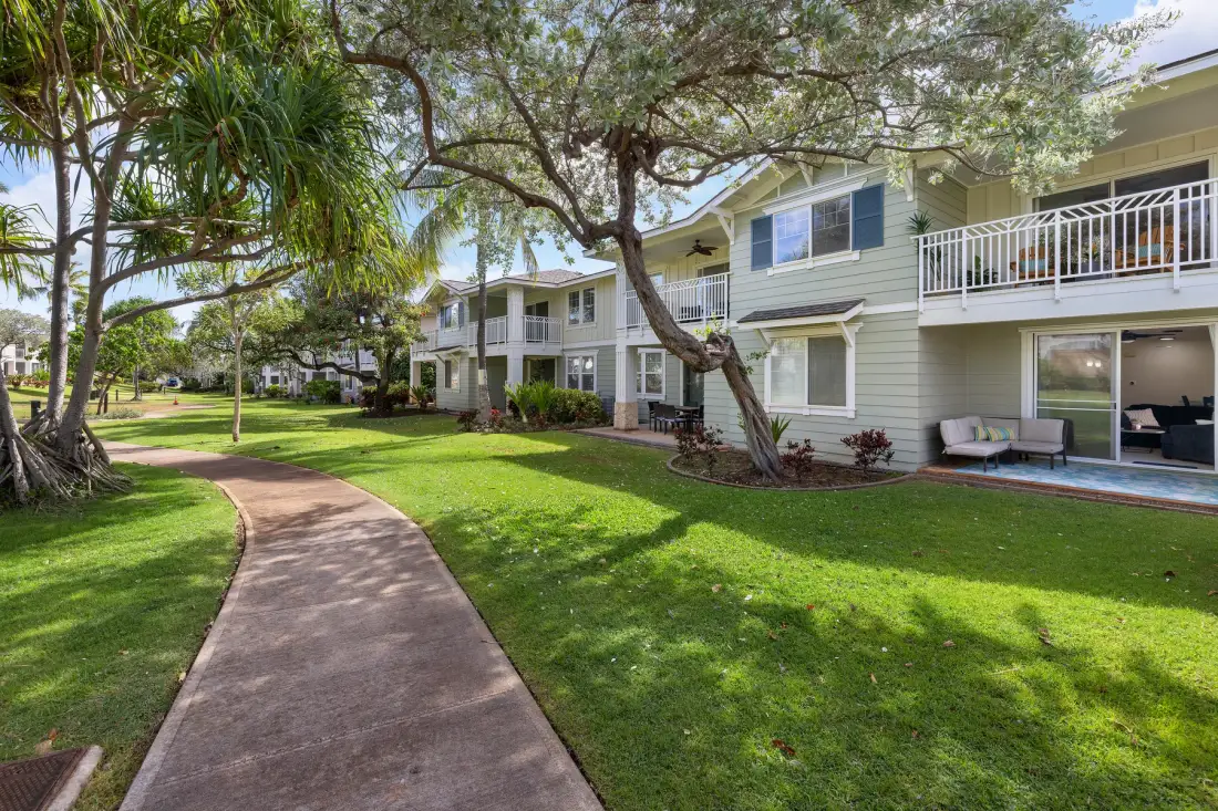 An outdoor walkway curves through a landscaped courtyard beside residential buildings.