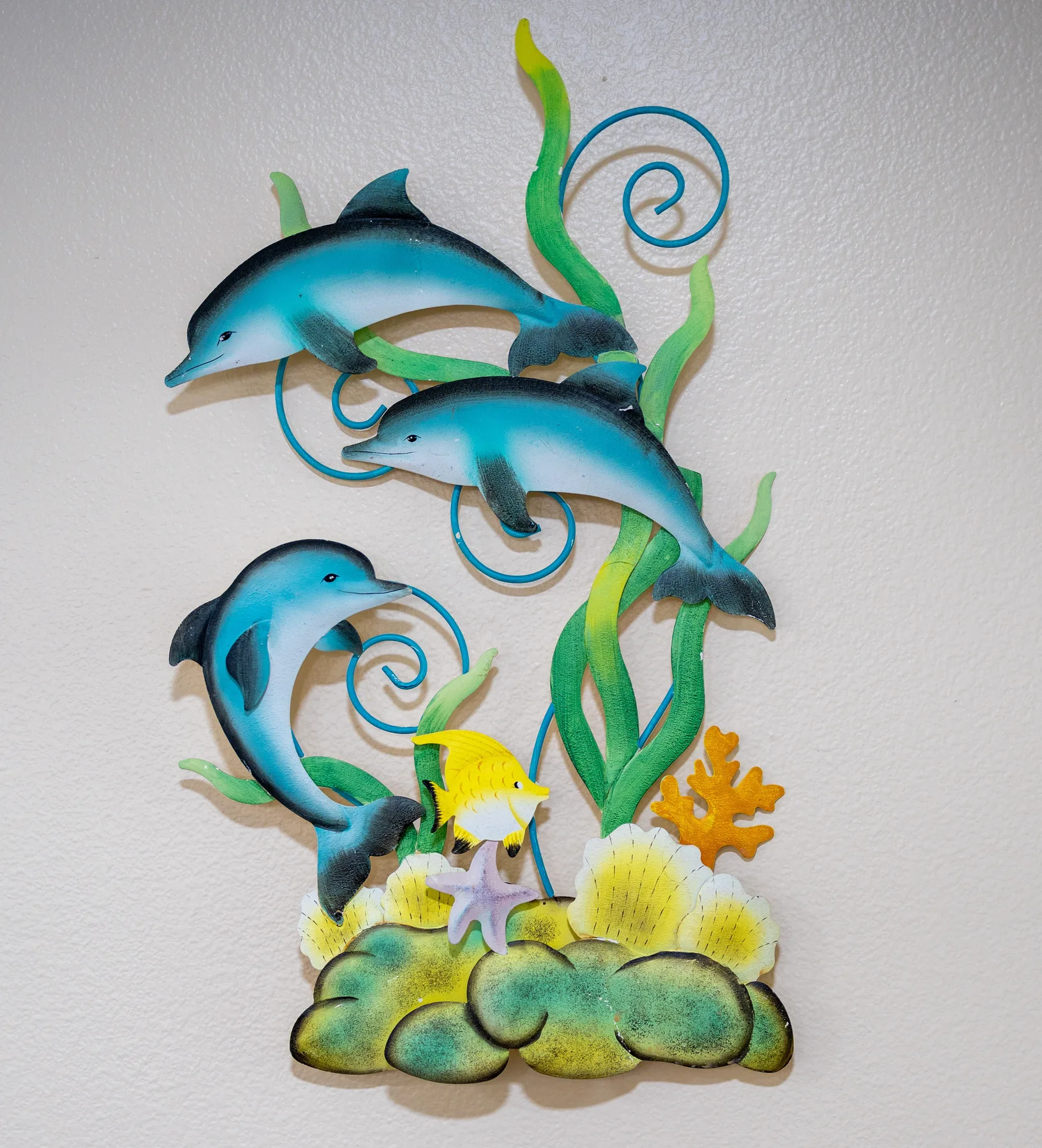 A colorful underwater wall decoration features dolphins, sea plants, and coral.