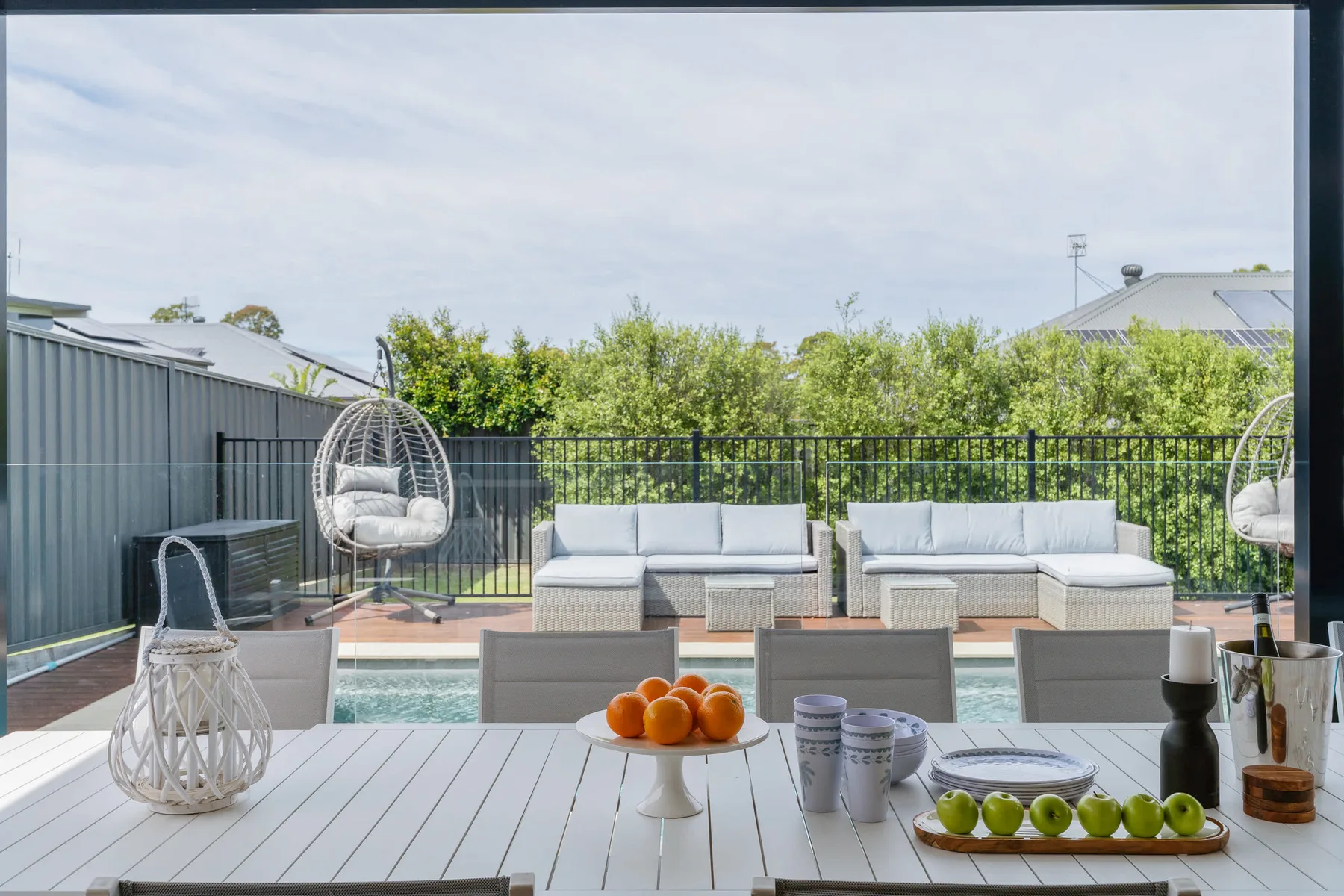 Patio al aire libre con piscina, asientos y vegetación junto a la barandilla.