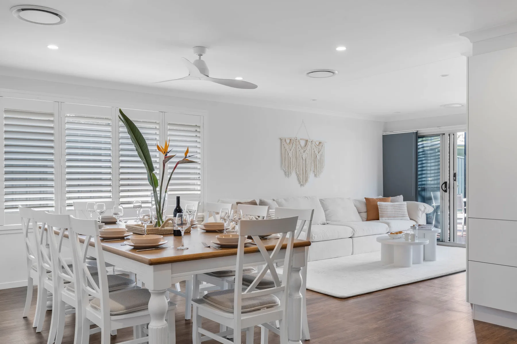 Una luminosa sala de estar y comedor con asientos blancos y una mesa puesta.