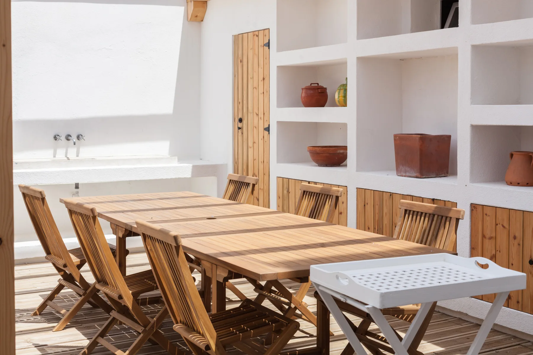 Un comedor luminoso con una mesa larga de madera junto a estantes empotrados.