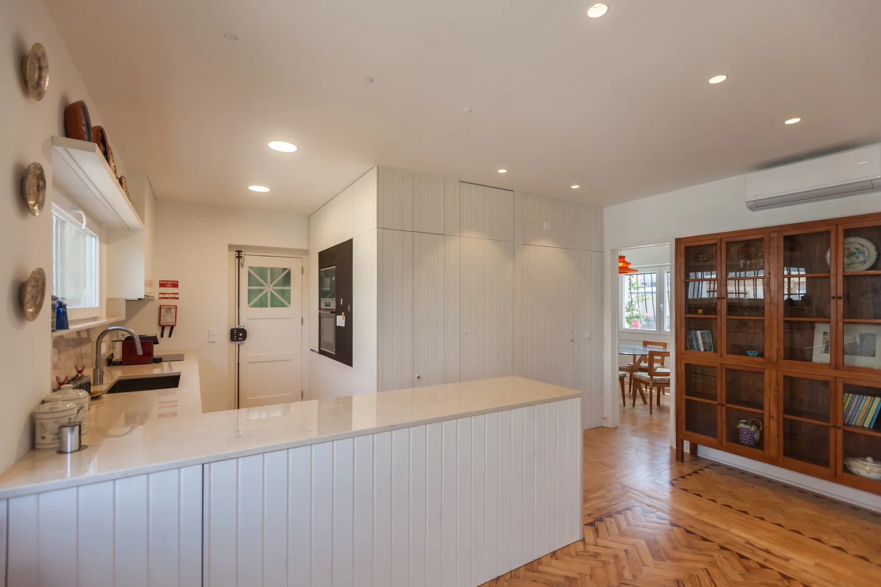 Una cocina luminosa con una isla larga y suelo de madera.