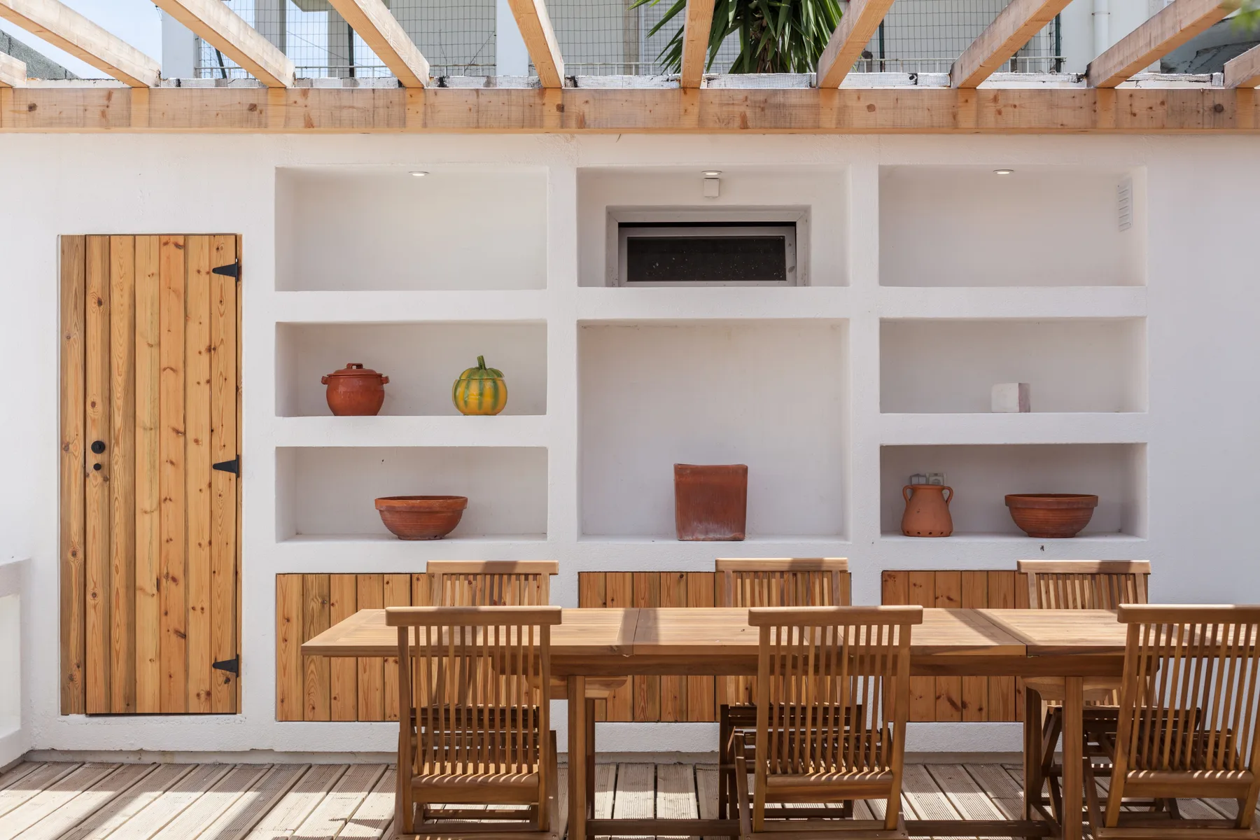 Una mesa de comedor de madera y sillas están frente a estantes empotrados.