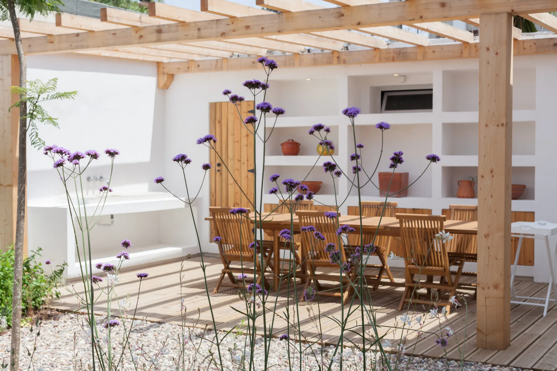 Una zona de comedor exterior con asientos de madera bajo una pérgola.