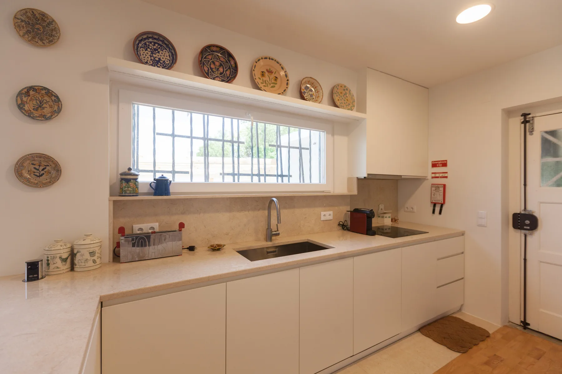 Una cocina luminosa con una encimera larga, fregadero y ventana amplia.