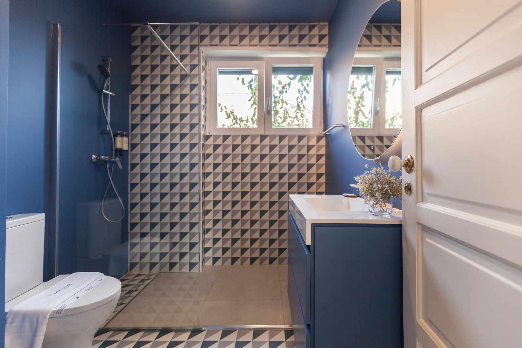 Un baño con azulejos estampados, una ducha, un inodoro y un lavabo.