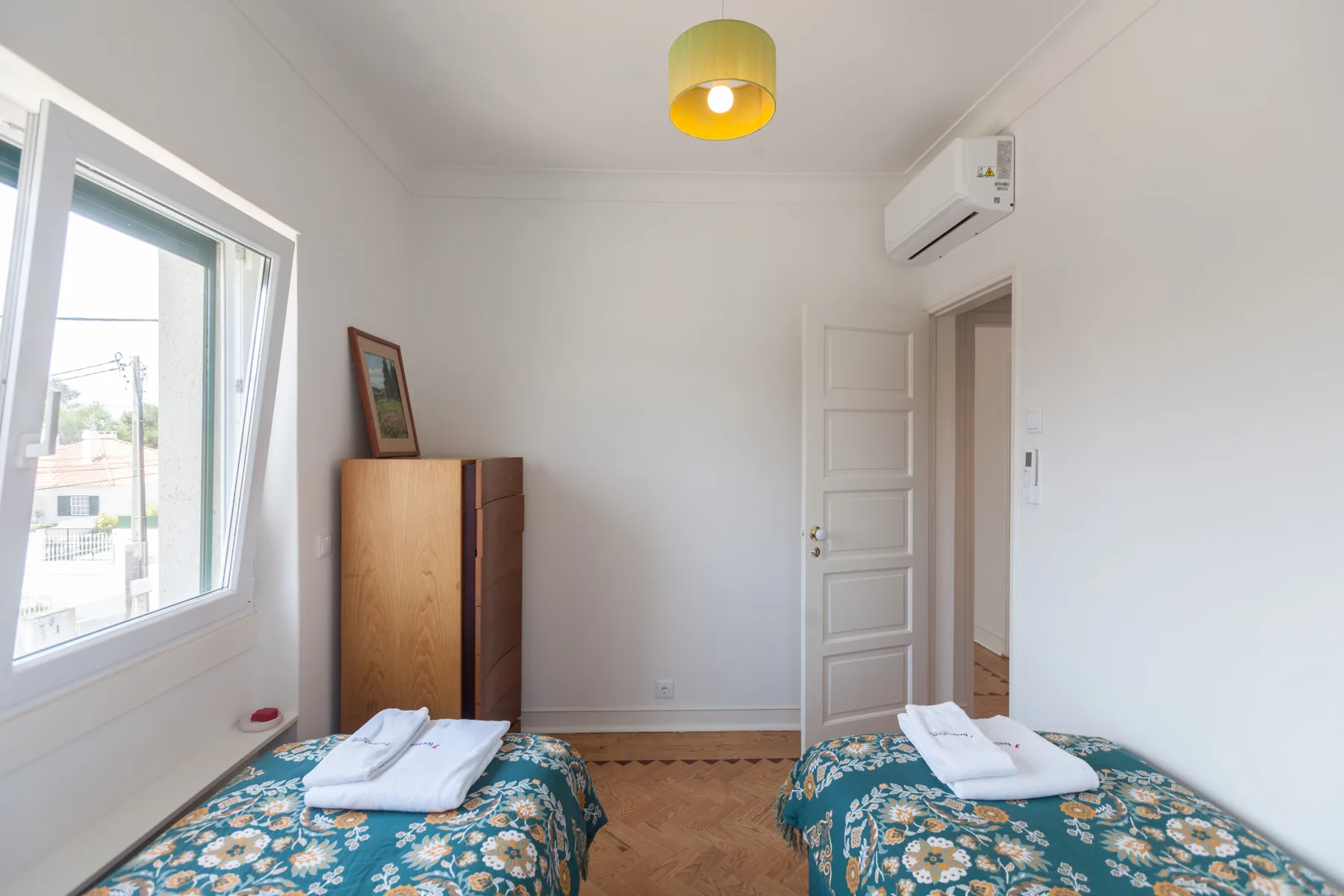 Un dormitorio con dos camas, ropa de cama estampada y una ventana.