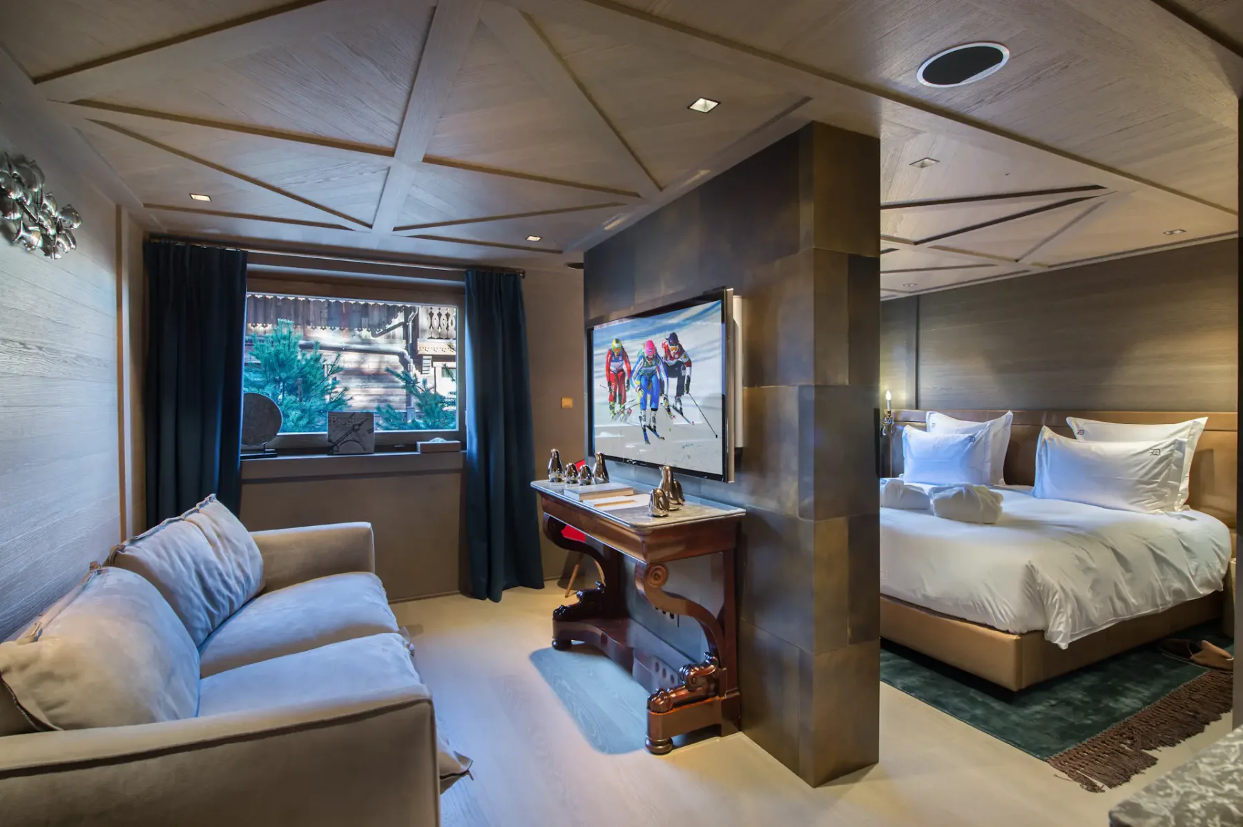 Un dormitorio con cama, sofá y escritorio bajo un techo geométrico.