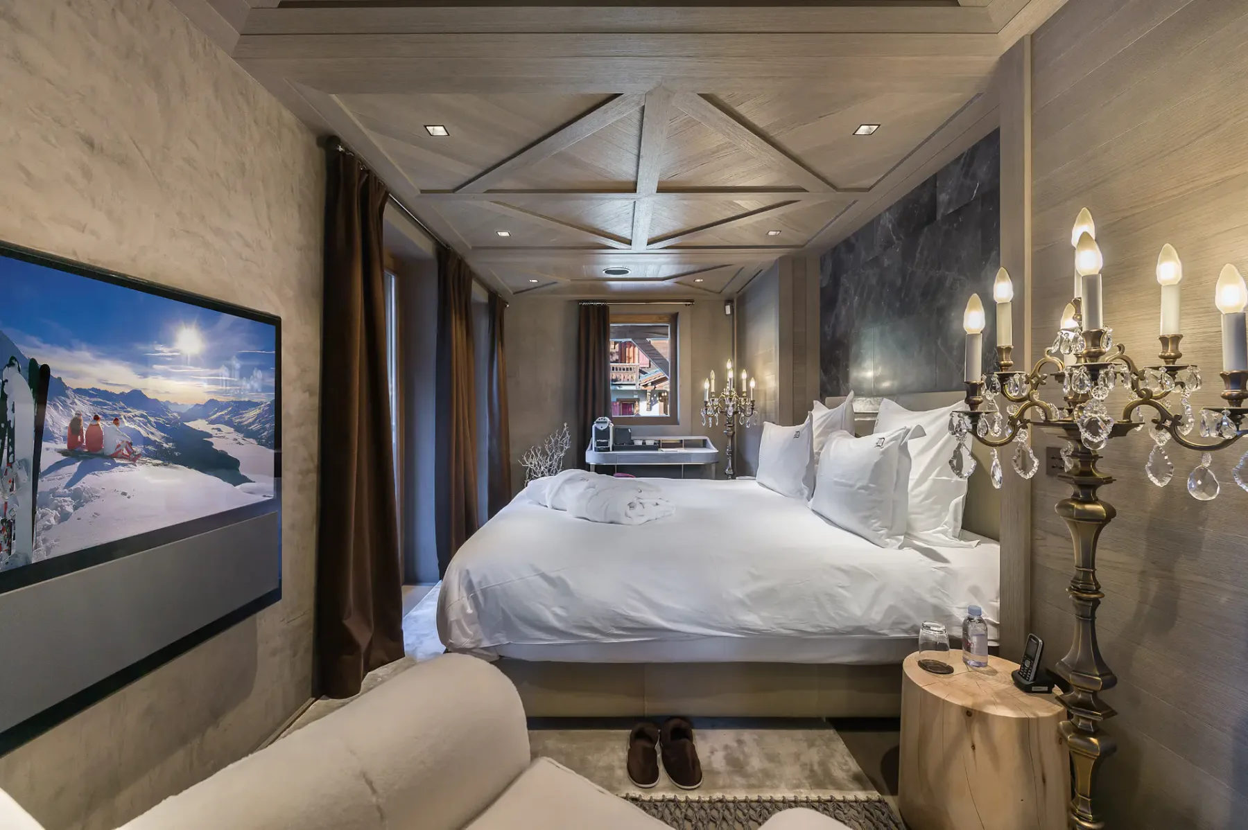 Un dormitorio con una cama grande, un televisor montado en la pared y una lámpara decorativa.