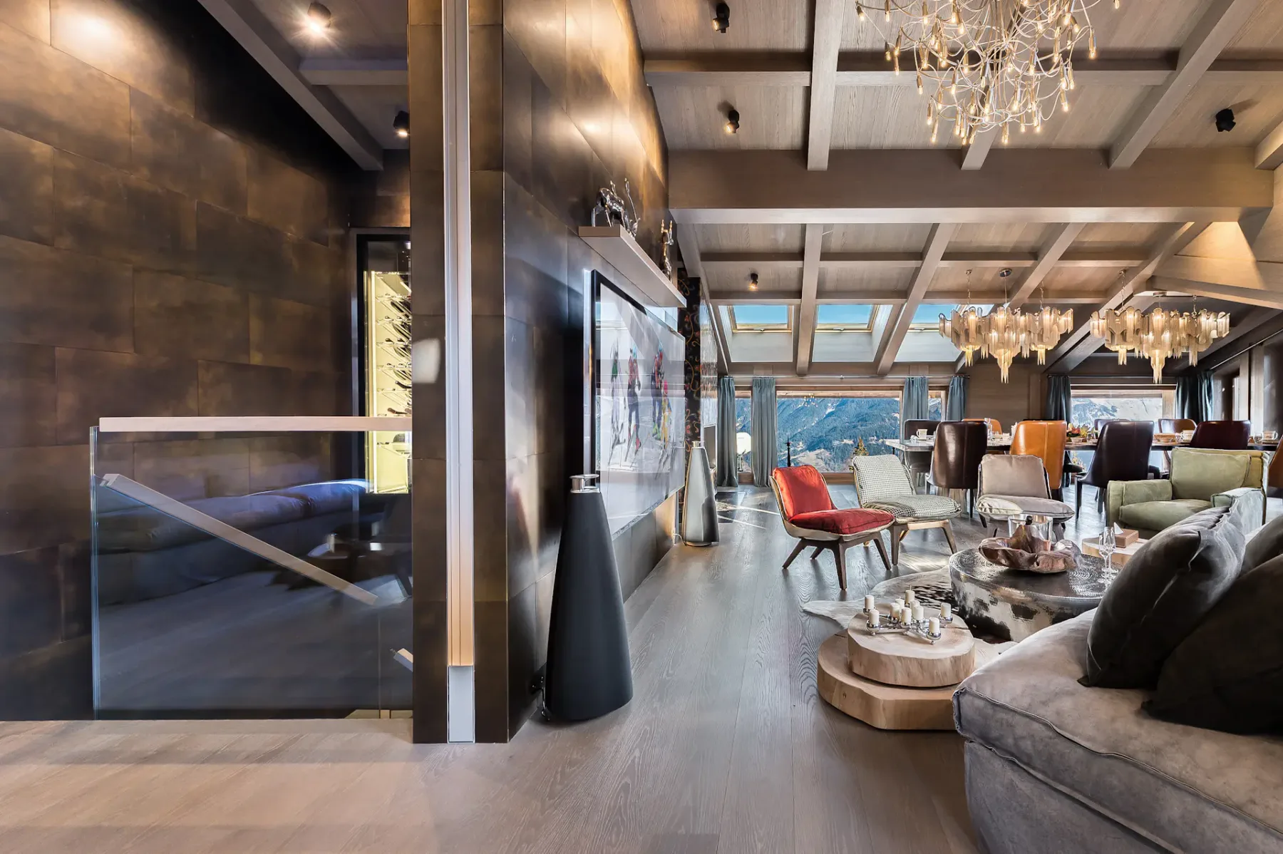 Luxurious living room with modern decor, chandeliers, plush seating, and large windows offering a scenic mountain view.