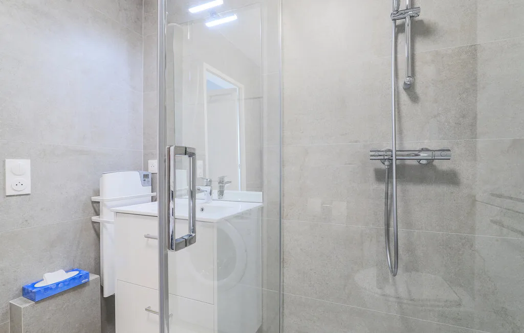 A bathroom with a glass shower and a sink vanity.