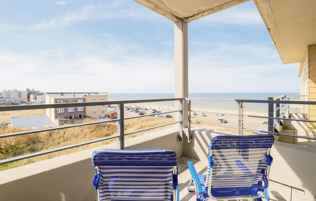 A balcony with striped seating overlooks a sandy beach and the sea.
