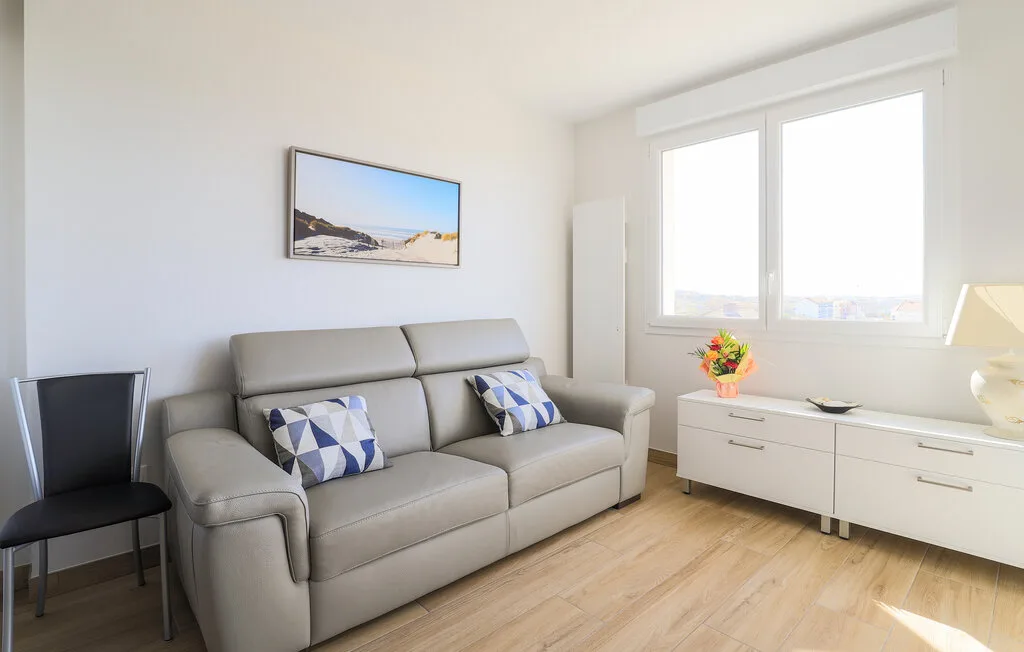 A bright living room with gray seating beside a large window.