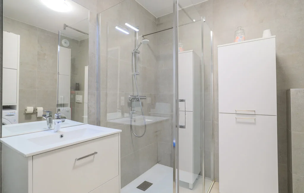 A bright bathroom with a sink, mirror, and glass-enclosed shower.