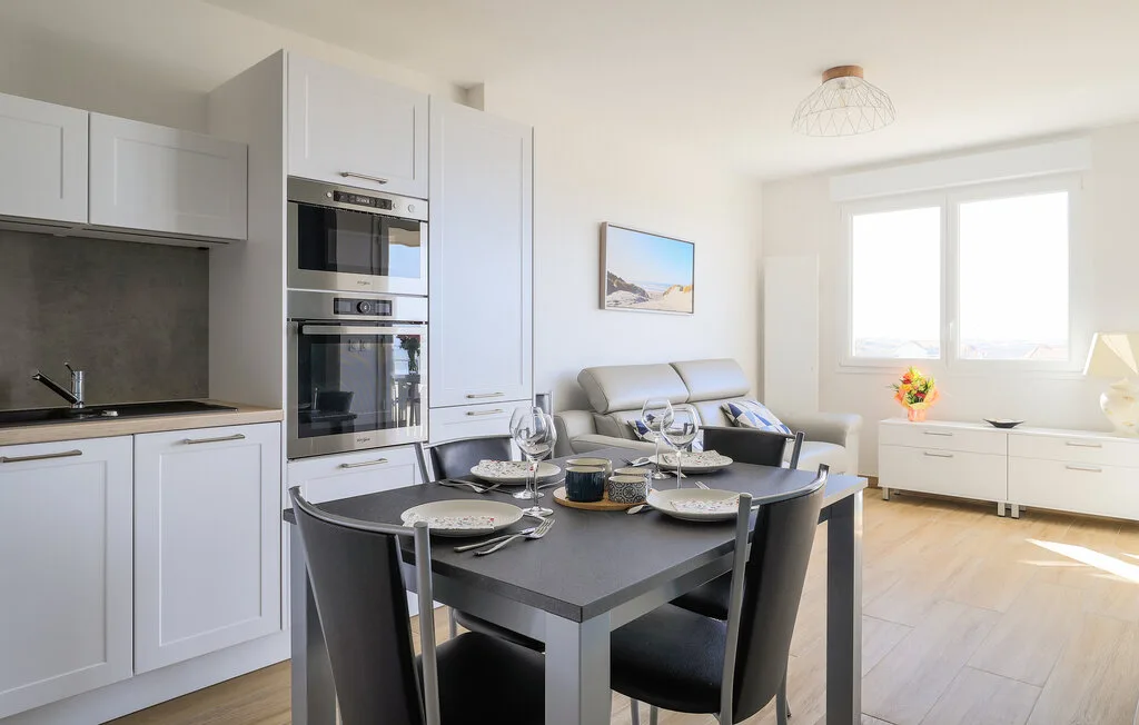 A bright open-plan kitchen and dining area with a table set for a meal.