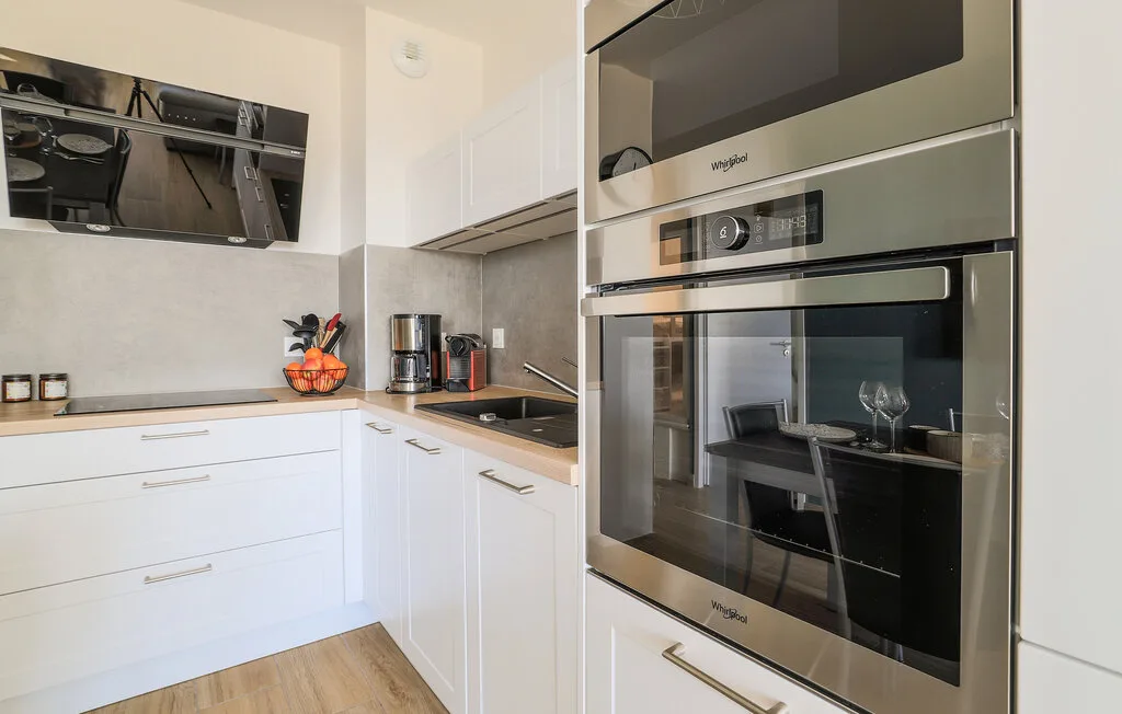 A modern kitchen with white cabinetry, a cooktop, and built-in ovens.