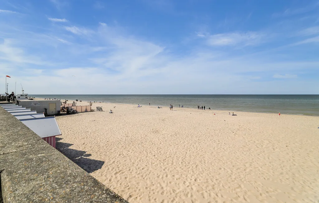 A broad sandy beach stretches along the water beneath a blue sky.