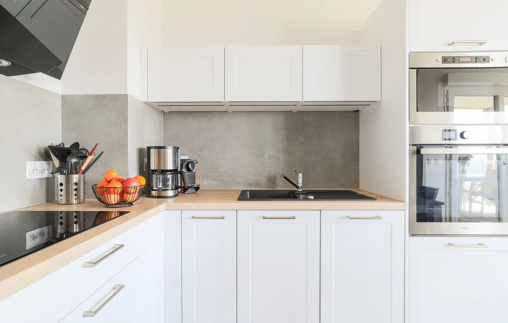 Una cocina luminosa con armarios blancos, una placa de cocción y un fregadero.